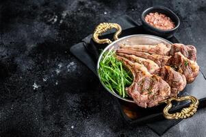 Grilled Lamb mutton Chops steaks in a skillet with green salad. Black background. Top view. Copy space photo