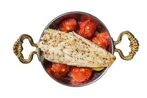 Roasted Haddock fish fillet in skillet with tomato and potato. Isolated, white background. photo