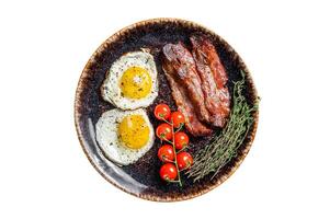 Breakfast with fried eggs and bacon with herbs in plate. Isolated on white background. photo