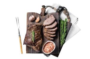 Roast and sliced tri tip beef steak on a wooden board with herbs. Isolated, white background. photo