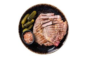 Grilled meat - Pork steaks from neck fillet meat in plate with pickled cucumbers. Isolated on white background. photo