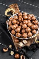 Macadamia nuts in a shell ready to eat. Black background. Top view photo