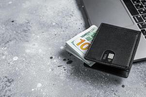 Workplace with stylish leather wallet with money, Laptop. Gray background. Top view. Copy space photo
