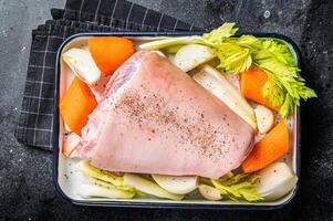 Cooking of Schweinshaxe from Raw pork shank knuckle with vegetables and herbs. Black background. Top view photo
