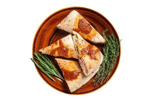 Calzone pizza pieces on rustic plate with tomato sauce and herbs. Isolated on white background. photo