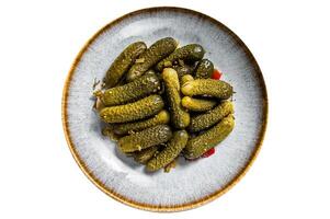 Plate with Pickled gherkins cucumbers on wooden board. Isolated on white background. photo