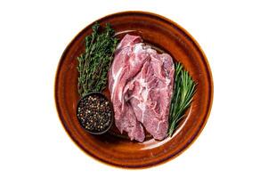 Raw piece of pork shoulder meat with spices on a rustic plate. Isolated on white background. photo
