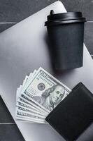 Top view of laptop, wallet with dollars and cup of espresso coffee. Black background. Top view. Copy space photo