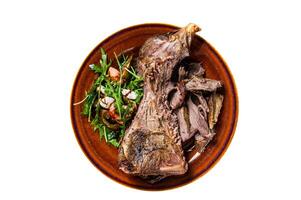 Grilled goat or lamb mutton shoulder meat in a rustic plate with salad. Isolated, white background. Top view. photo