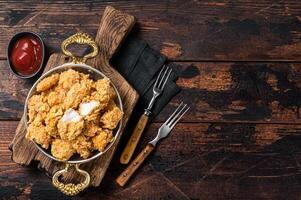 Homemade Crispy Popcorn Chicken bites in a skillet. Wooden background. Top view. Copy space photo