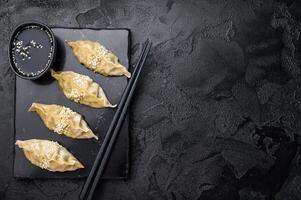 Steamed Chinese Jiaozi Dumplings with meat and vegetables on marble board. black background. top view photo