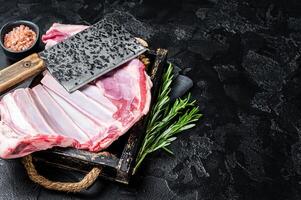 Butcher table with Rack of lamb, raw mutton ribs with meat cleaver. Black background. Top view. Copy space photo