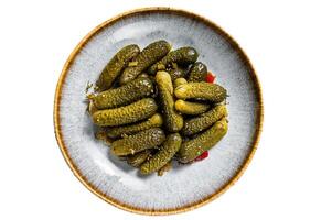 Plate with Pickled gherkins cucumbers on wooden board. Isolated on white background photo