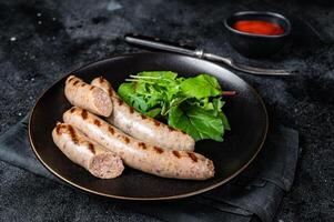 BBQ Grilled pork sausages served with greens. Black background. Top view photo