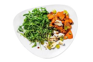 Salad with arugula, baked pumpkin and brie cheese. Isolated on white background, Top view. photo