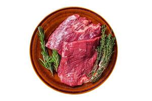 Two Flap or Flank raw beef steaks on a rustic plate with herbs. Isolated, white background. Top view. photo