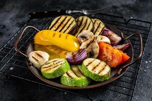 Grilled vegetables, bell pepper, zucchini, eggplant, onion and tomato. Black background. Top view photo