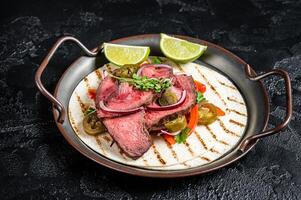 Carne Asada Tacos with grilled steak, green sauce, jalapenos and onion, Mexican food. Black background. top view photo