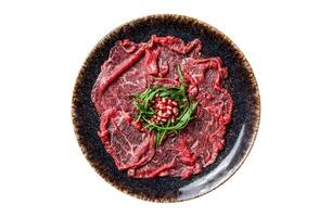 Carpaccio marbled beef meat with arugula and pomegranate seeds. Isolated, white background. Top view. photo