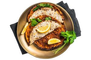 Turkish lahmacun pizza with mince meat and tomatoes on a plate with parsley and lemon. Isolated, white background. photo