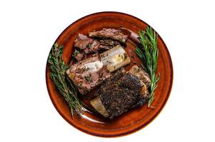 Grilled short beef ribs with thyme on a rustic plate. High quality Isolate, white background. photo