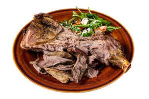 Grilled goat or lamb mutton shoulder meat in a rustic plate with salad. Isolated on white background. photo
