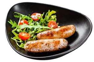 Grilled pork sausages with tomato and arugula salad. Isolated on white background. Top view. photo