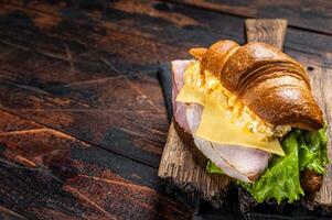 Croissant sandwich with egg cheese and green lettuce salad leaf, healthy breakfast. Wooden background. Top view. Copy space photo