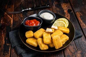 Fried Fish Sticks Fingers with sauce in a plate. Wooden background. Top view photo