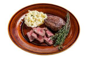 Sliced fillet mignon or tenderloin beef steak on a rustic plate with mashed potato. Isolated on white background, top view.background. Top view photo