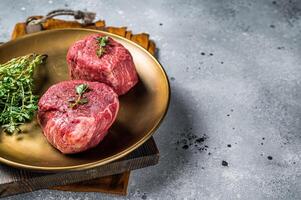 Dry aged Fillet Mignon Beef steak with herbs, raw marble meat. Gray background. Top view. Space for text photo