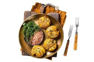 Crushed, smashed potatoes baked with rosemary and thyme on plate. Isolated, white background. photo