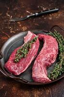 Raw Bavette or Sirloin flap beef meat steak with thyme. Dark background. Top view photo
