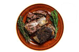 Grilled short beef ribs with thyme on a rustic plate. Isolated on white background. photo