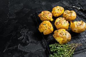 Crushed, smashed potatoes baked with rosemary and thyme. Black background. Top view. Copy space photo