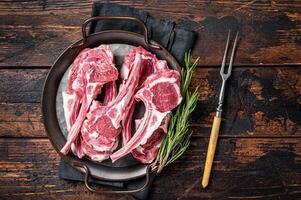 Raw lamb mutton chop steaks, fresh meat cutlets on butcher table. Black background. Top view photo