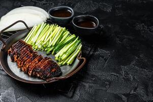 Peking Duck served with cucumber, green onions, and roasted wheaten chinese pancakes with sauce Hoysin. Black background. Top view. Copy space photo