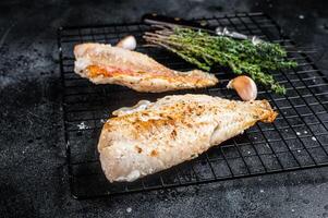 Grilled sea red perch fillet, Snapper fish on a rack. Black background. Top view photo