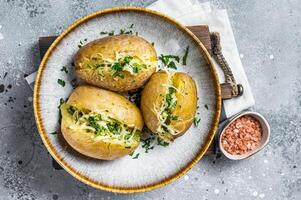 Baked Jacket potatoes with cheese and butter. Gray background. Top view photo