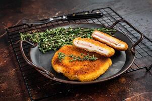Cordon bleu chicken fillet cutlet with ham and cheese. Dark background. Top view photo