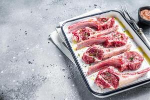 Ready for cooking raw lamb chop steaks with spices and herbs. Gray background. Top view. Copy space photo