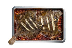 Flounder flat fish roasted in a tomato sauce in baking tray. Isolated background photo