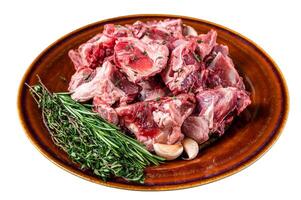 Raw mutton meat diced for goulash or stew with bone on a rustic plate. Isolated on white background. photo
