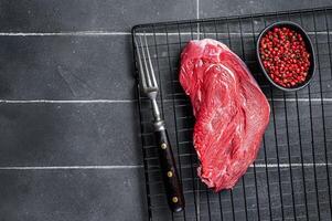 Raw beef meat piece for grilling with spices. Black background. Top view. Copy space photo