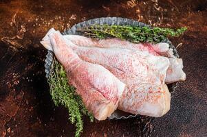 Raw ocean red perch fillet, Snapper fish with herbs. Dark background. Top view photo