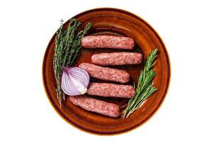 Raw kofta meat kebabs sausages on a plate with herbs. Isolated, white background. Top view. photo