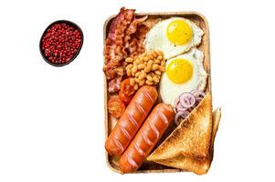 English Breakfast in a wooden tray with fried eggs, sausages, bacon, beans and toasts. Isolated on white background, Top view. photo