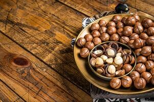 Organic Macadamia nuts in a shell ready to eat. Wooden background. Top view. Copy space photo