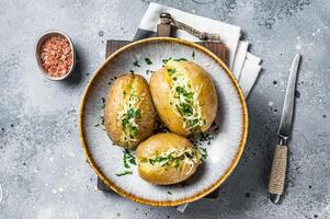 Baked Jacket potatoes with cheese and butter. Gray background. Top view photo