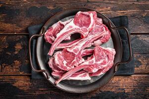 Raw lamb mutton chop steaks, fresh meat cutlets on butcher table. Black background. Top view photo